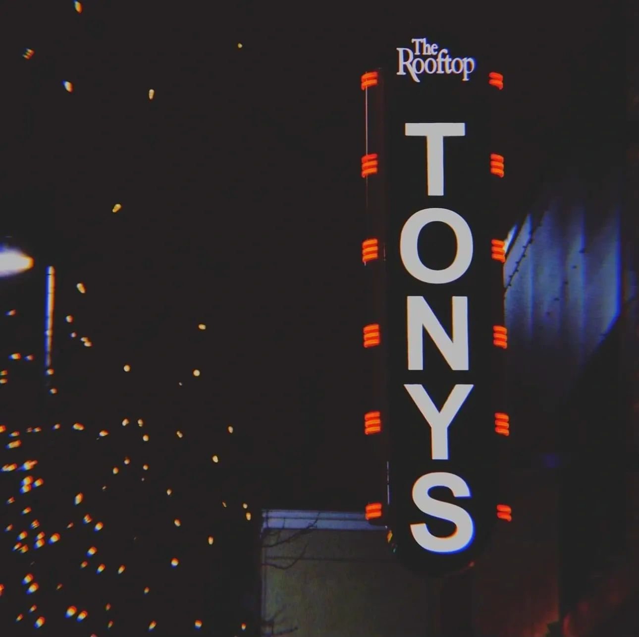 Tony's vertical blade sign lit at night on College Avenue, The Rooftop on top